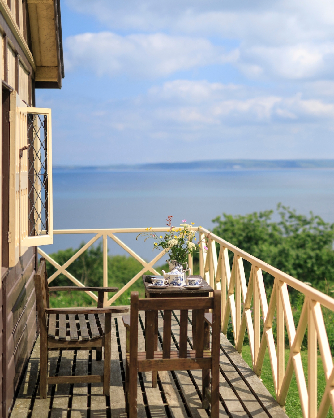 Wooden veranda with a table and chairs overlooking the sea