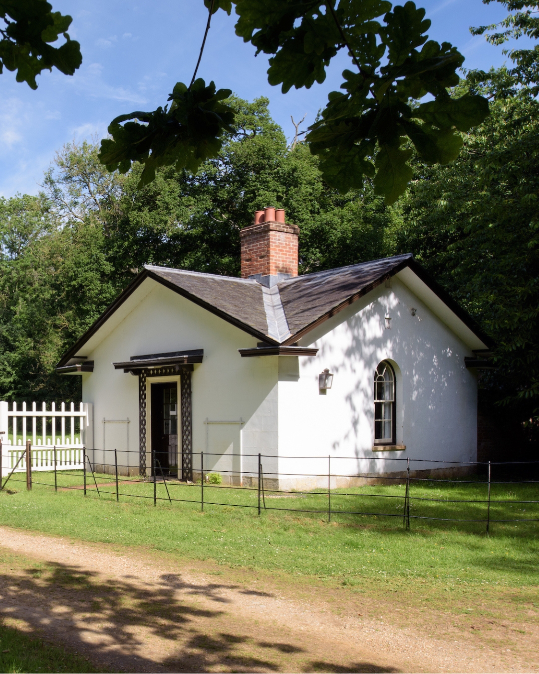 A small white gatehouse surrounded by trees