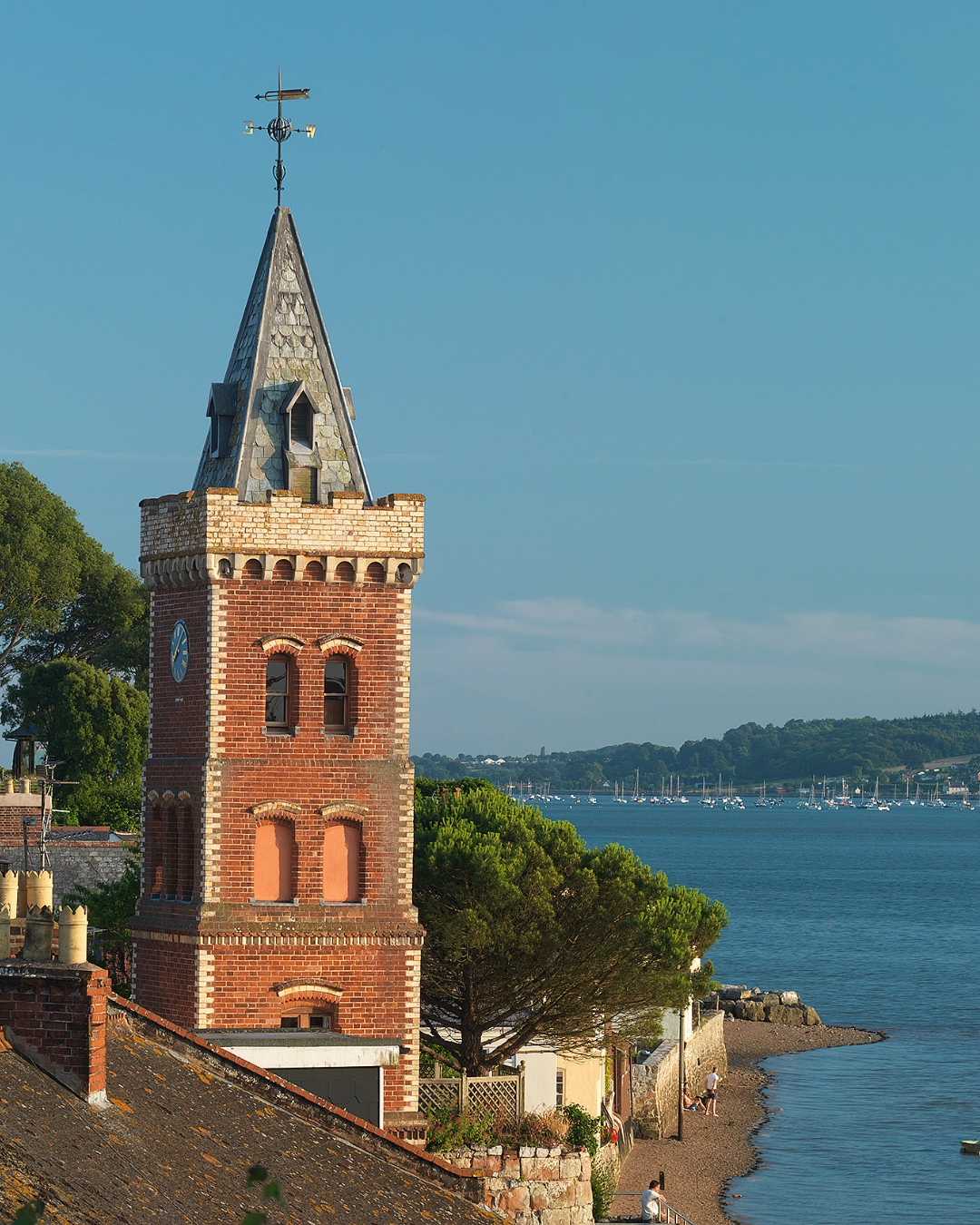 A tall tower with a pointed roof overlooking the sea