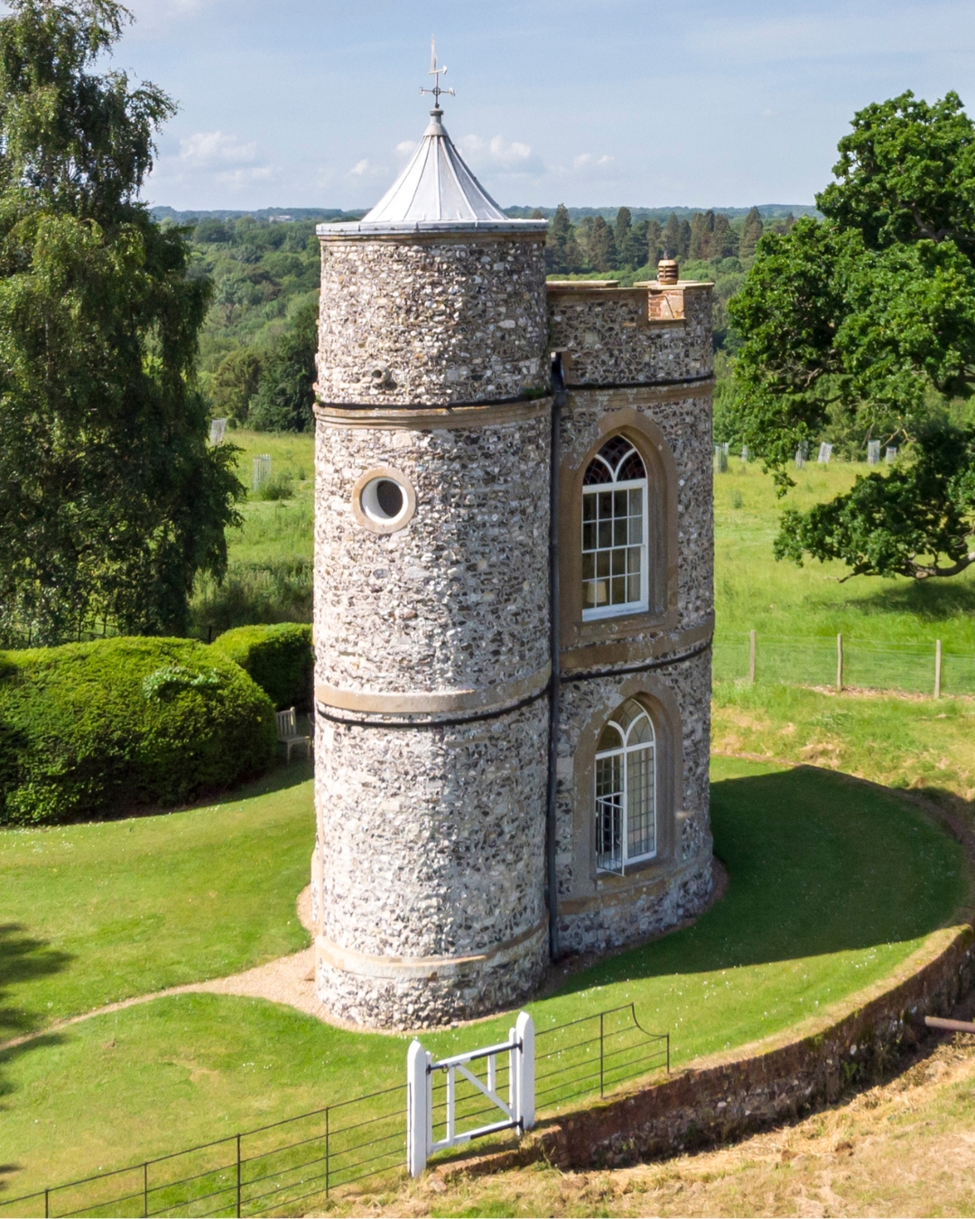 A tower folly with a turret surrounded by fields