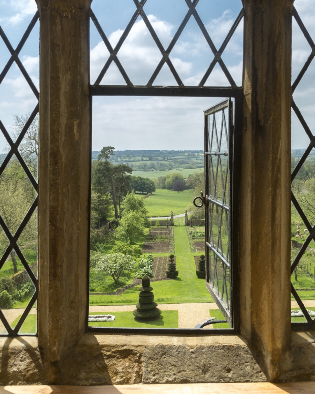 View through an open leaded window to gardens below