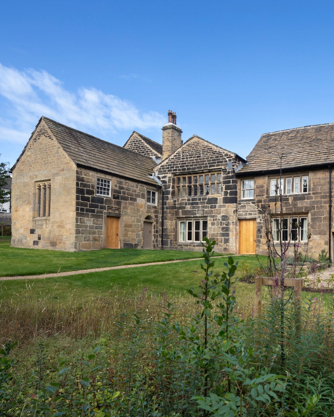 A medieval stone manor house surrounded by green lawns