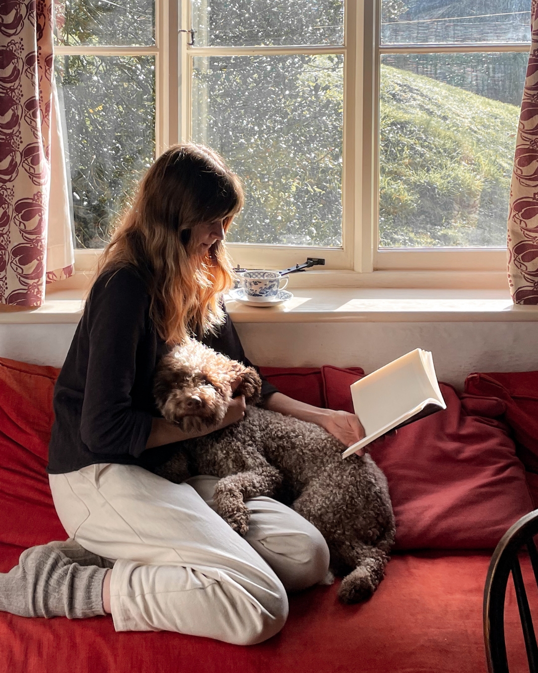 Woman with dog reading in front of a window